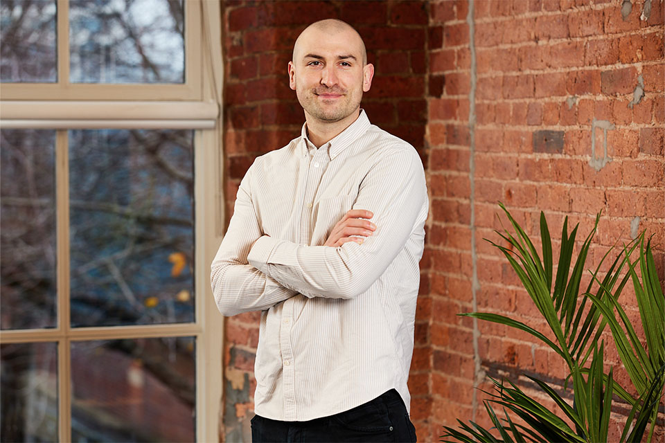 Business owner smiling with arms crossed after business coaching meeting in Glasgow